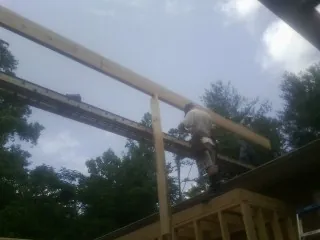 Carpenter setting a ridge beam over a new addition frame — Ice Dam Removal by Roofing Brothers in Elloree