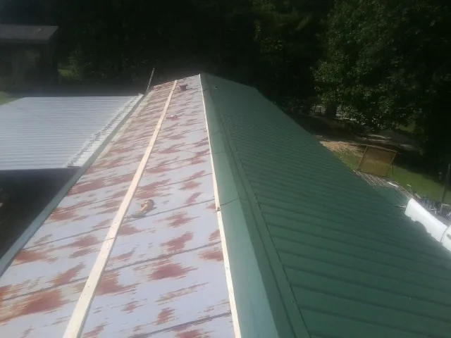 Old rusted panels beside newly installed green metal roofing — Wind Damage Roof Repair by Roofing Brothers in Elloree