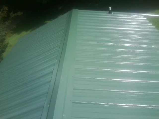 New green metal panels meeting at the ridge of a roof — Flat Roof Repair work by our crew in Elloree