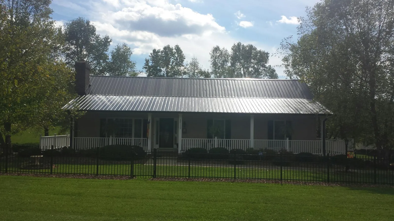 Gray metal roof on a brick ranch with a full width front porch — Gutter Guard Installation work by our crew in Elloree