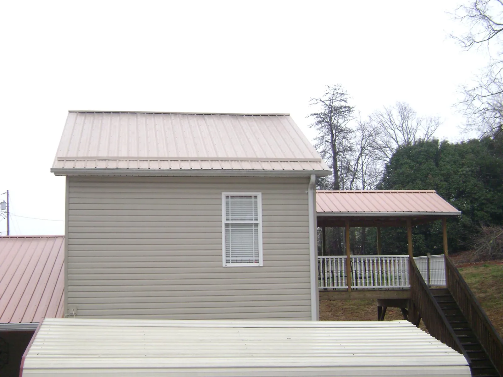 Tan metal roofs on a two story addition and attached porch, from a Roof Replacement job in Elloree
