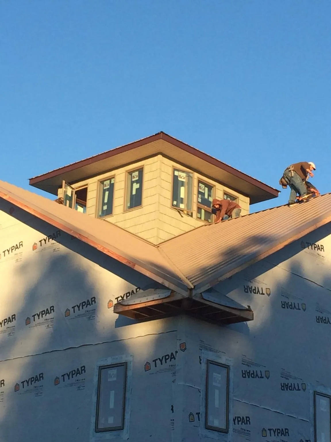 Roofers working around a rooftop cupola on a new metal roof at sunset — Roof Waterproofing in Elloree by Roofing Brothers